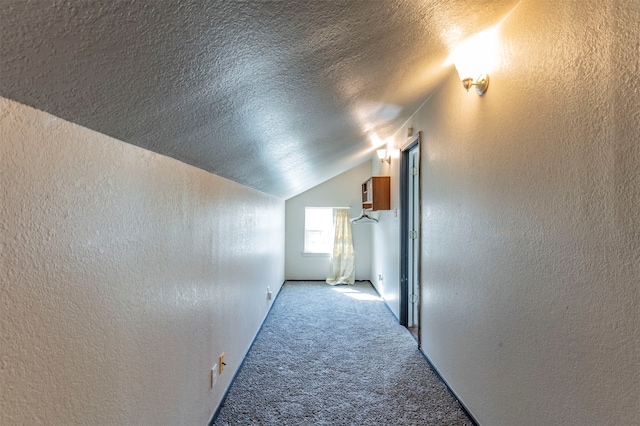 corridor featuring light colored carpet, a textured ceiling, and vaulted ceiling