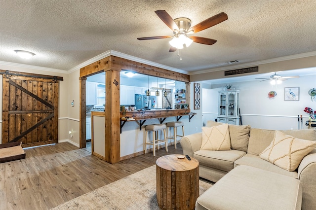 living room with ornamental molding, hardwood / wood-style flooring, a barn door, and a textured ceiling