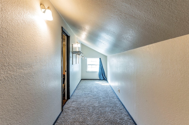 hallway with lofted ceiling, carpet flooring, and a textured ceiling