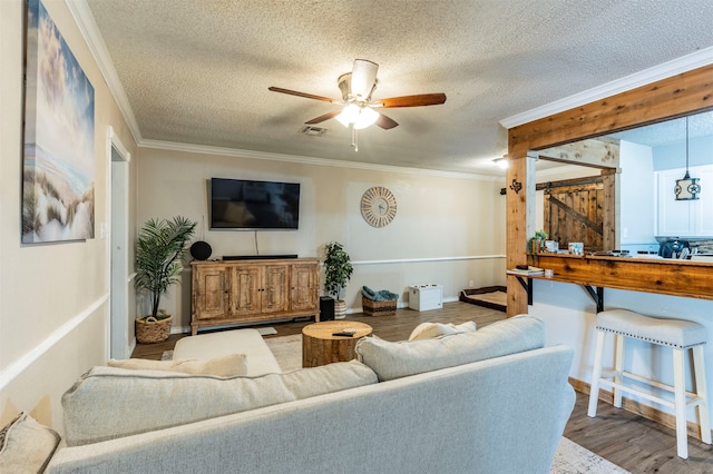 living room featuring ceiling fan, crown molding, hardwood / wood-style floors, and a textured ceiling