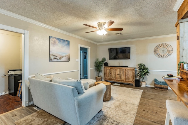 living room featuring wood-type flooring, ceiling fan, crown molding, and a textured ceiling