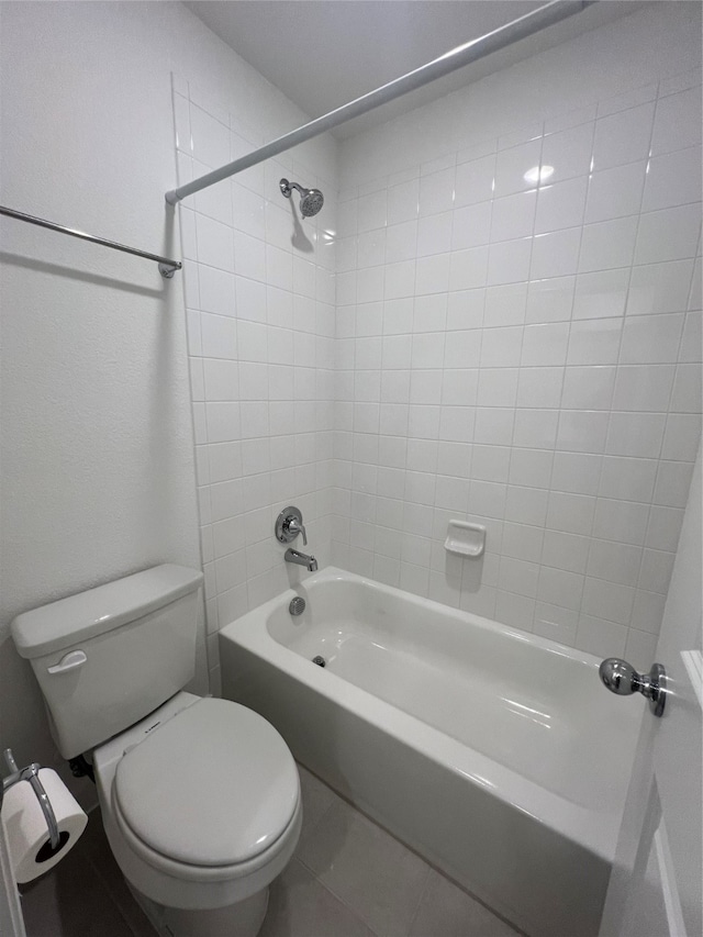 bathroom featuring tiled shower / bath, tile patterned flooring, and toilet