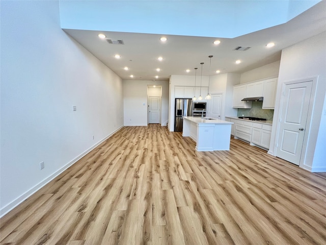 kitchen featuring white cabinets, pendant lighting, a kitchen island with sink, stainless steel appliances, and light hardwood / wood-style floors