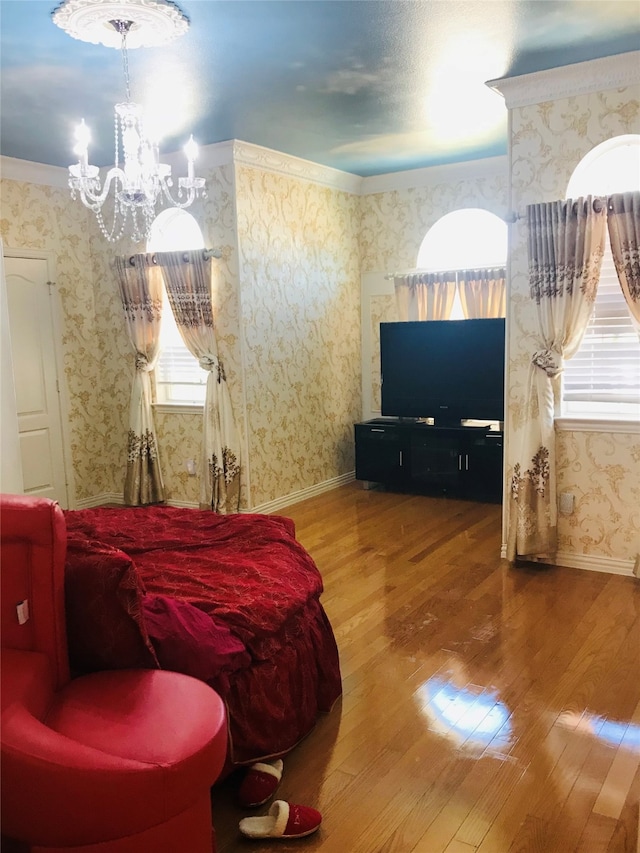 bedroom featuring a notable chandelier, ornamental molding, and wood-type flooring