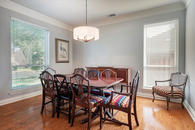 dining space with hardwood / wood-style floors and ornamental molding