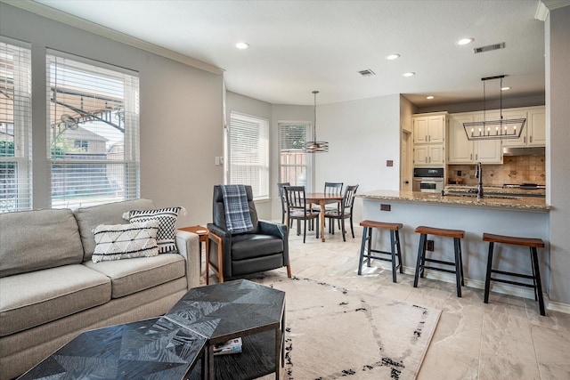 living room with a wealth of natural light, crown molding, and a chandelier