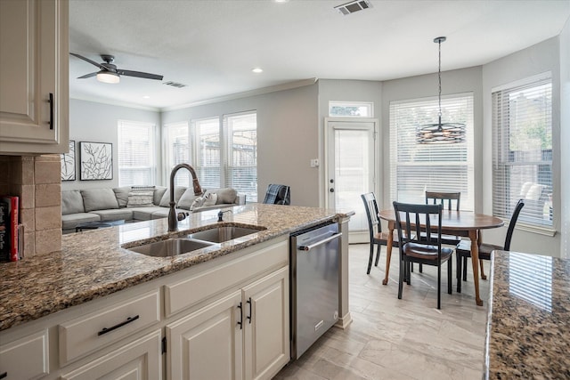 kitchen featuring dishwasher, stone counters, sink, and hanging light fixtures