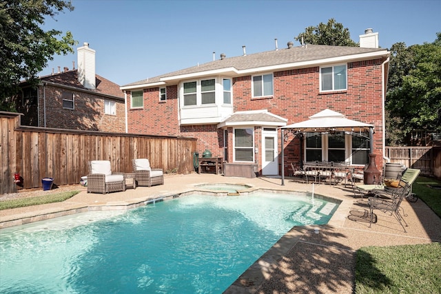 rear view of property featuring a gazebo, a swimming pool with hot tub, and a patio