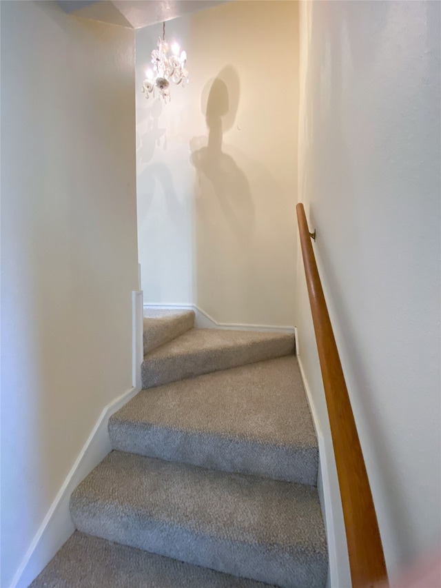 staircase featuring carpet and an inviting chandelier