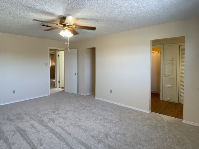 spare room with light colored carpet, a textured ceiling, and ceiling fan