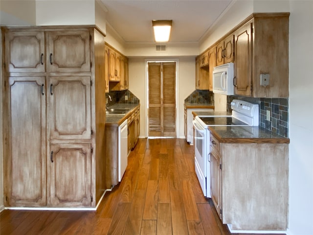 kitchen with hardwood / wood-style flooring, backsplash, sink, and white appliances