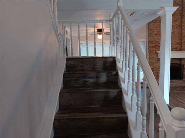 stairway with brick wall, lofted ceiling, a brick fireplace, and hardwood / wood-style floors