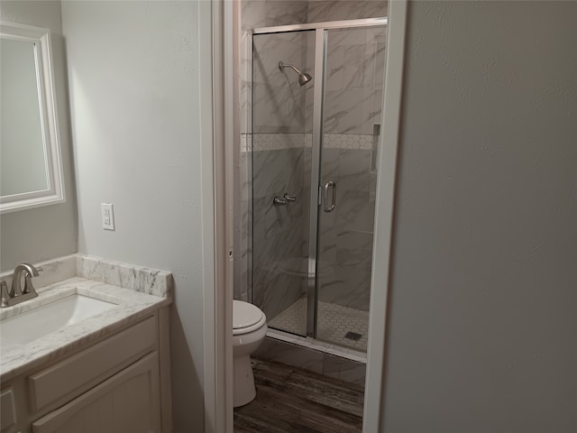 bathroom featuring vanity, hardwood / wood-style floors, toilet, and a shower with door