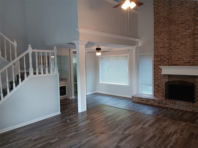 unfurnished living room with a fireplace, dark hardwood / wood-style floors, a high ceiling, and ceiling fan