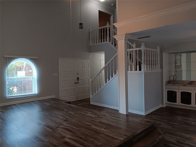 foyer entrance featuring a towering ceiling, dark hardwood / wood-style floors, and crown molding