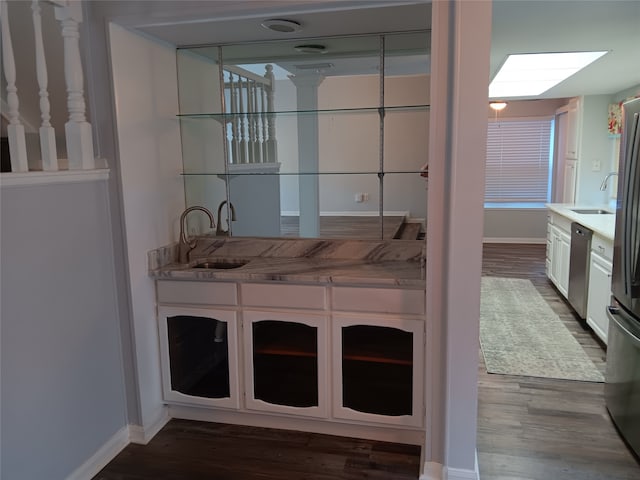 bar featuring white cabinets, dishwasher, dark wood-type flooring, and sink