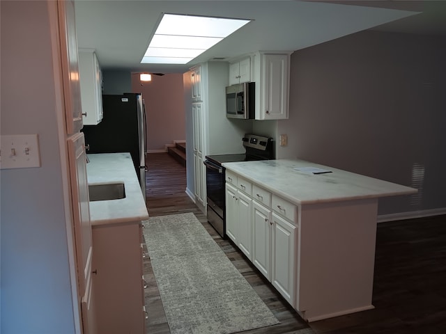 kitchen with dark wood-type flooring, kitchen peninsula, white cabinetry, a breakfast bar area, and appliances with stainless steel finishes