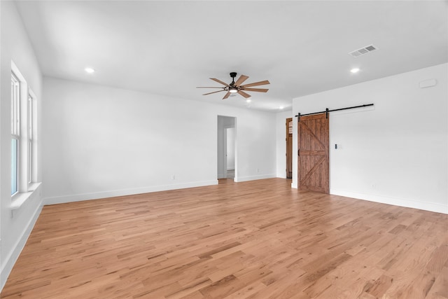 spare room featuring ceiling fan, light hardwood / wood-style floors, and a barn door