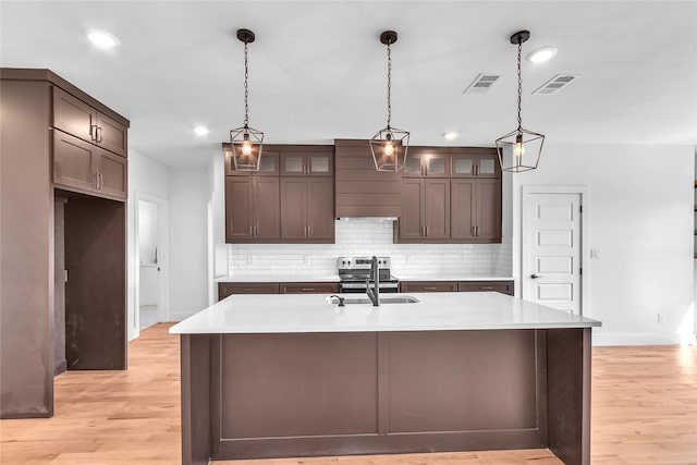 kitchen with light hardwood / wood-style flooring, a center island with sink, and sink