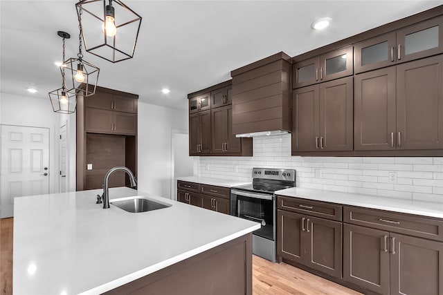 kitchen with stainless steel range with electric cooktop, an island with sink, light hardwood / wood-style flooring, and sink