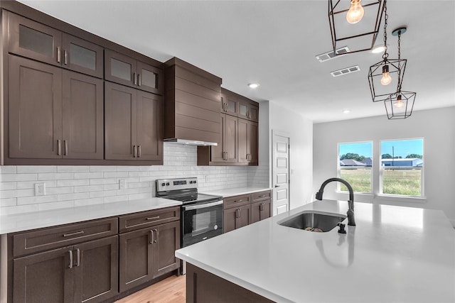 kitchen with light hardwood / wood-style floors, pendant lighting, electric range, sink, and decorative backsplash