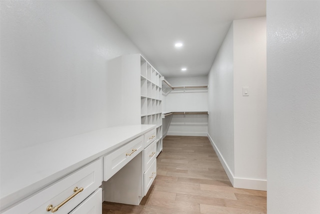 spacious closet featuring built in desk and light hardwood / wood-style flooring