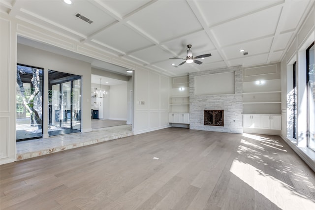 unfurnished living room featuring hardwood / wood-style floors, coffered ceiling, ceiling fan with notable chandelier, and built in shelves