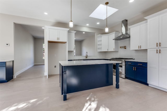 kitchen with decorative light fixtures, blue cabinets, white cabinets, high end range, and wall chimney exhaust hood