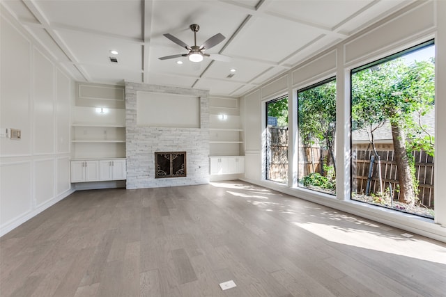 unfurnished living room with light hardwood / wood-style floors, ceiling fan, coffered ceiling, and built in shelves