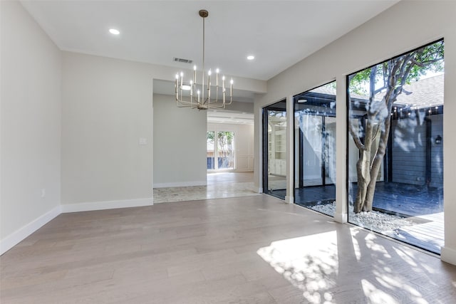 empty room with a notable chandelier and light hardwood / wood-style flooring