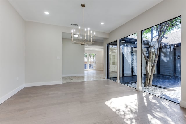 spare room featuring a chandelier and light hardwood / wood-style floors