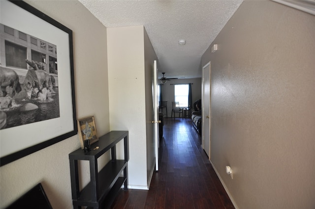 corridor featuring a textured ceiling and dark wood-type flooring