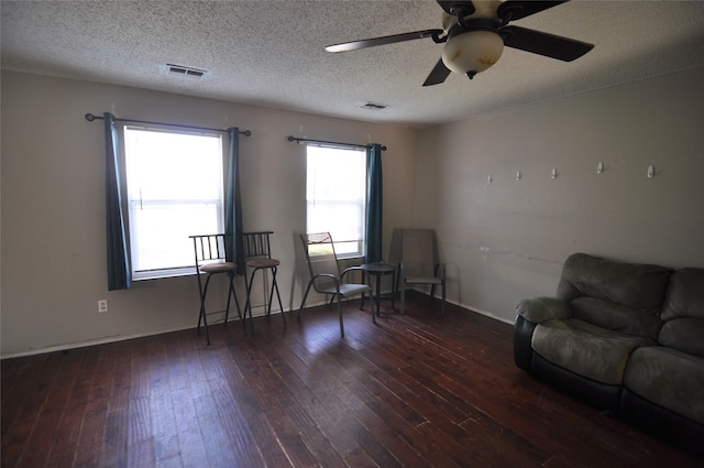 living area with ceiling fan, a textured ceiling, and dark hardwood / wood-style floors