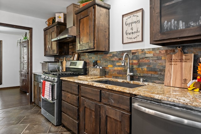 kitchen with wall chimney range hood, dark brown cabinetry, sink, stainless steel appliances, and light stone countertops