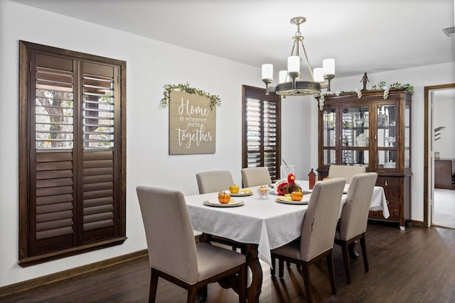 dining area with an inviting chandelier and dark wood-type flooring