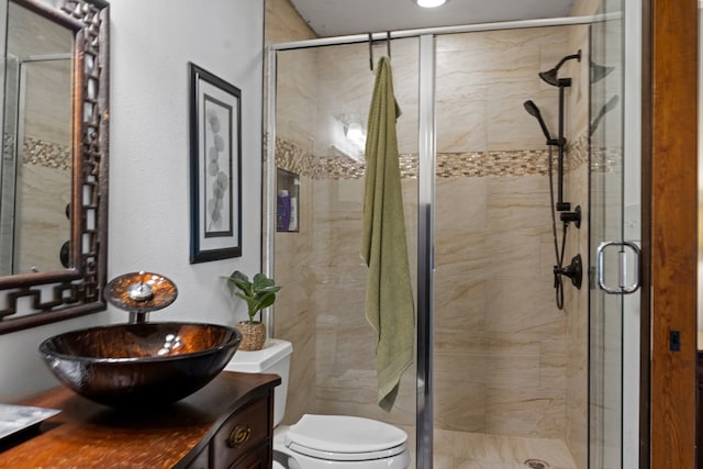 bathroom featuring a shower with door, vanity, and toilet