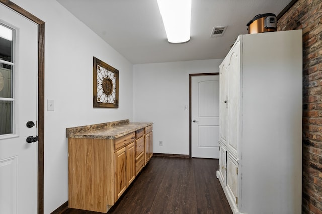 kitchen featuring brick wall and dark hardwood / wood-style flooring