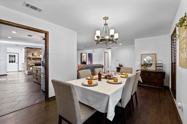 dining space with a fireplace, a chandelier, and dark hardwood / wood-style flooring