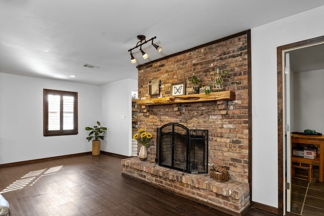 living room featuring a brick fireplace and dark hardwood / wood-style flooring