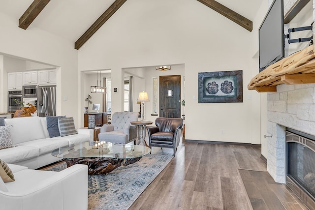 living room featuring a stone fireplace, dark hardwood / wood-style floors, beam ceiling, and high vaulted ceiling