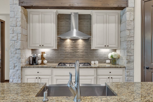 kitchen featuring light stone counters, wall chimney exhaust hood, and white cabinets