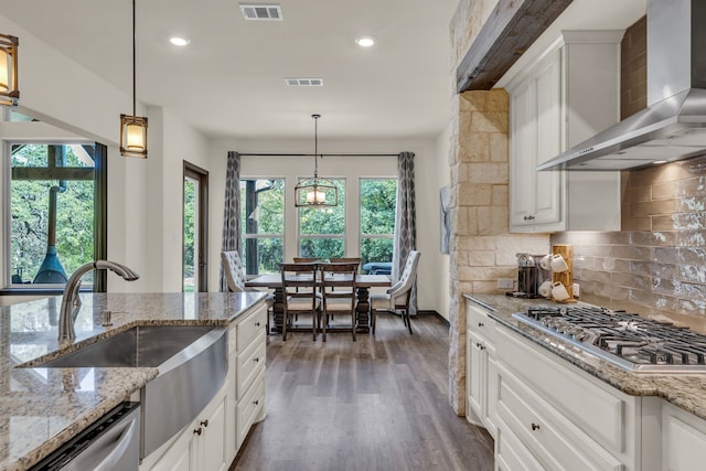 kitchen with appliances with stainless steel finishes, wall chimney range hood, white cabinetry, and dark hardwood / wood-style flooring