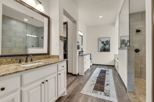 bathroom featuring hardwood / wood-style flooring, vanity, and tiled shower