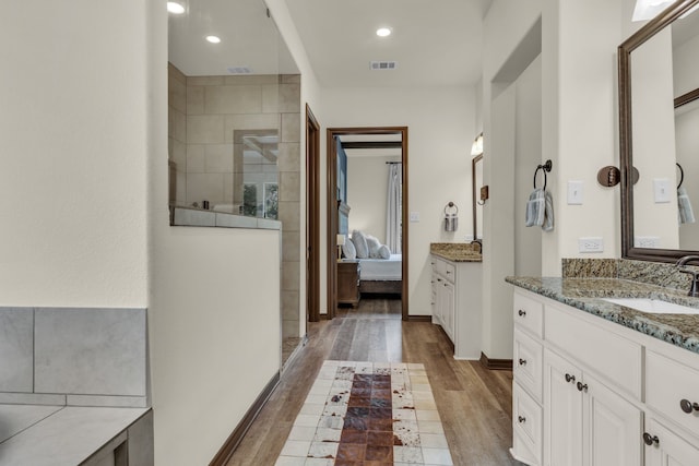 bathroom with a tile shower, hardwood / wood-style floors, and vanity