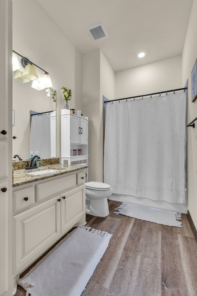 full bathroom featuring shower / tub combo, hardwood / wood-style floors, vanity, and toilet