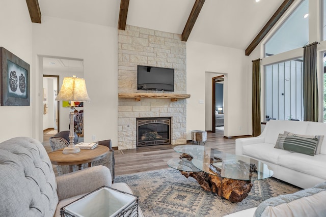 living room with hardwood / wood-style floors, vaulted ceiling with beams, and a stone fireplace