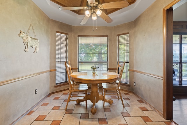 dining area featuring ceiling fan, a tray ceiling, and a wealth of natural light