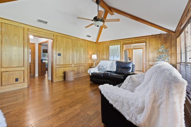 living room with ceiling fan, wooden walls, beam ceiling, and hardwood / wood-style floors