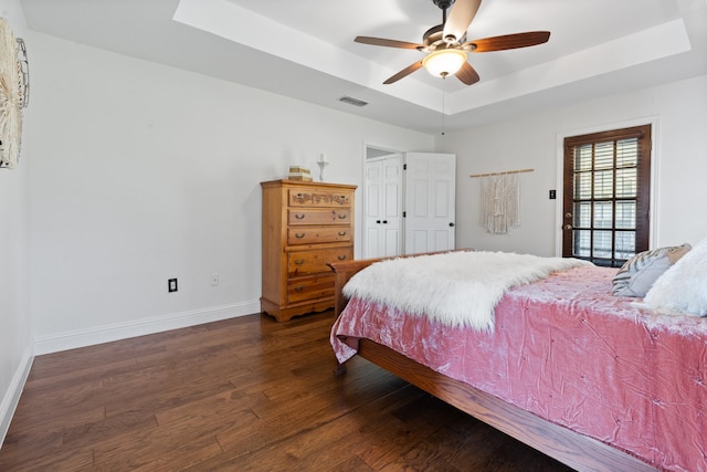 bedroom featuring ceiling fan, a raised ceiling, and dark hardwood / wood-style flooring