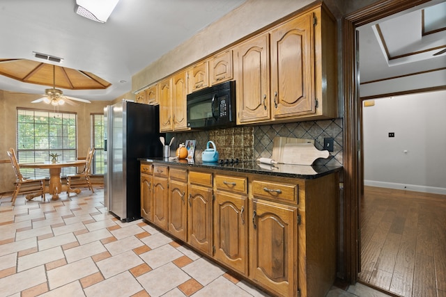 kitchen featuring ceiling fan, a raised ceiling, tasteful backsplash, black appliances, and light wood-type flooring